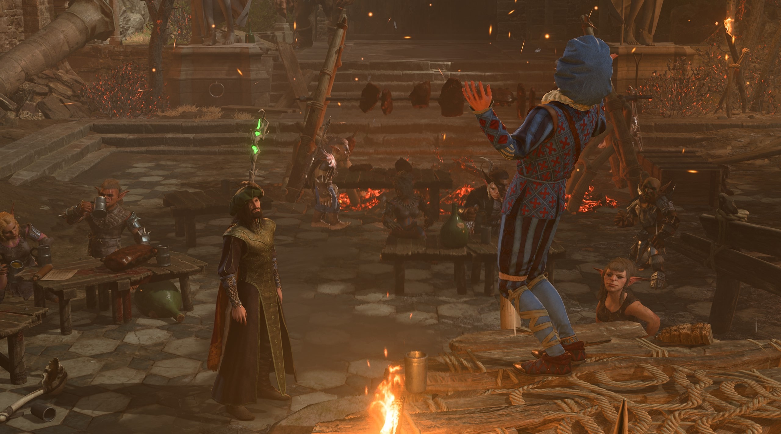 Screenshot Baldur's Gate 3. Zu sehen ist ein Platz voller Goblins. Auf einer kleinen Tribüne steht Volo und hält ein Schauspiel ab. Ein menschlicher Magier betrachtet skeptisch die Szenerie. 