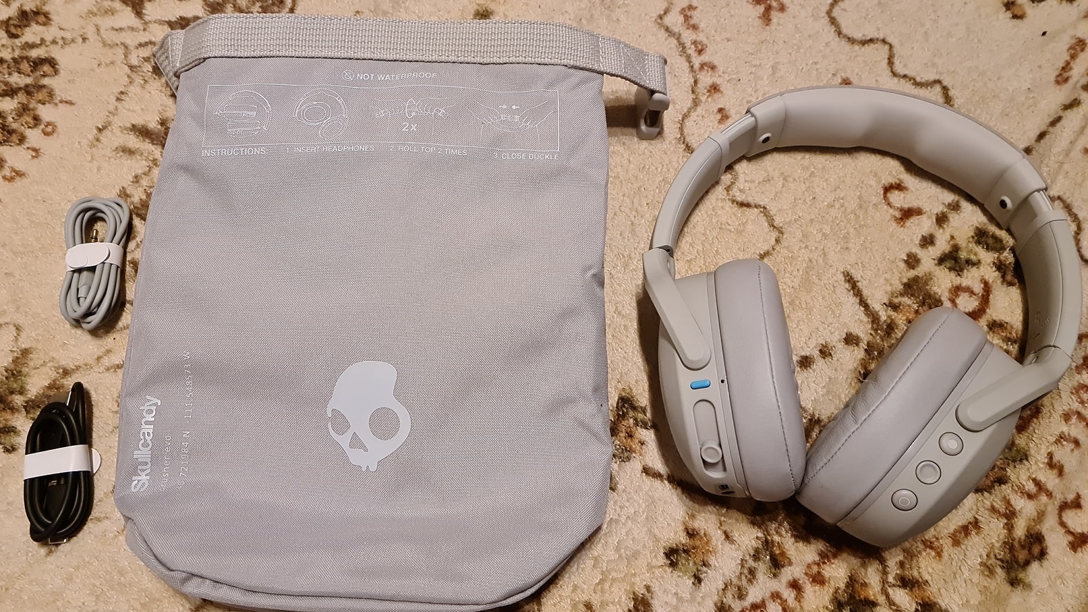 Zu sehen ist der Inhalt der Crusher Evo – neben den Kopfhörern liegt eine wattierte Tragetasche bei, sowie ein USB-C-Ladekabel und ein AUX-Kabel. 