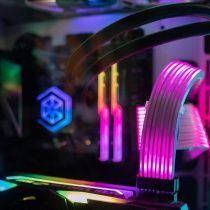 Dargestellt ist das Innenleben eines Gaming-PC. Zu sehen sind unter anderem zahlreiche Lüfter und eine Grafikkarte. Alles ist in bunte RGB Beleuchtung gehüllt.