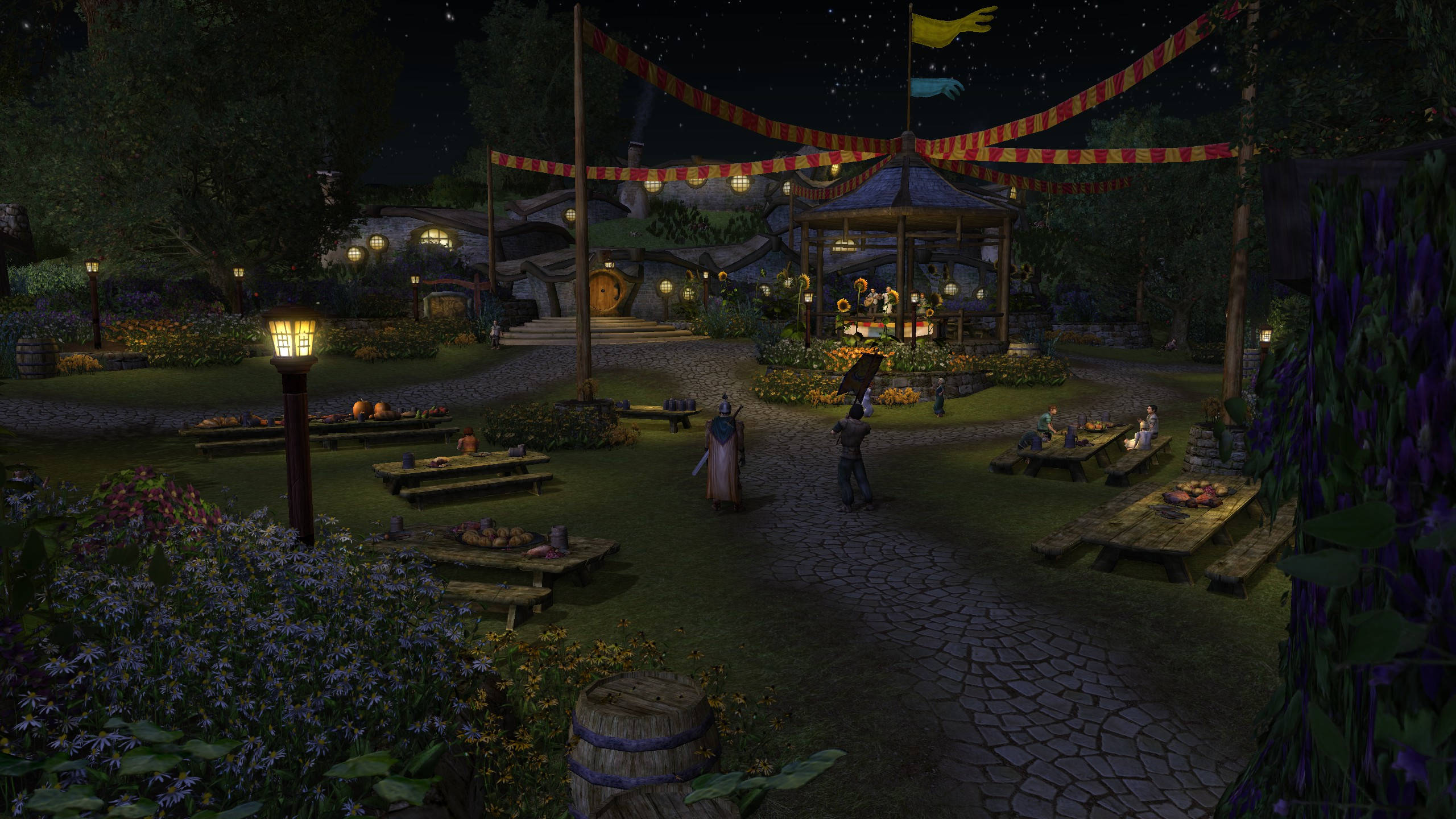 Screenshot aus Der Herr der Ringe Online. Zu sehen ist ein Dorf im Auenland in der Nacht. Zu sehen ist ein geschmückter kleiner Platz, gedeckte Tische und Hobbithöhlen. 